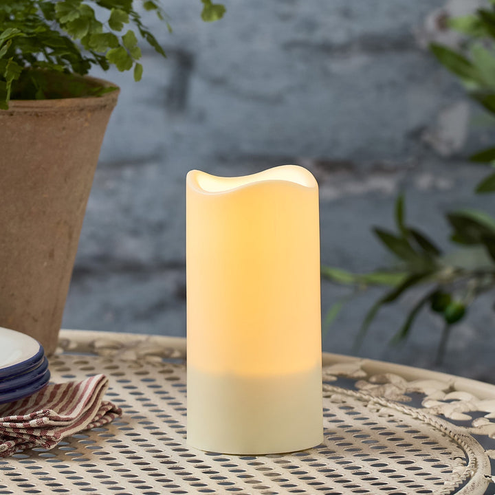 Drei LED Solarkerzen erleuchten gemütlich einen Balkon bei Nacht. Kabellose Gartenbeleuchtung, ideal für Ambiente auf Terrasse.