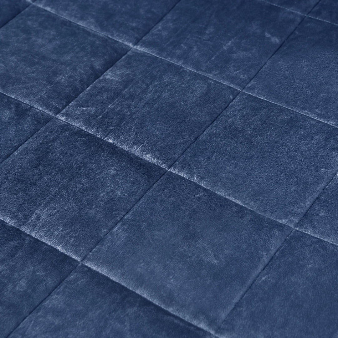 Schlafzimmer mit gefalteter, beschwerter Decke auf dem Bett. Eine ruhige Schlafhilfe für Entspannung und Antistress.