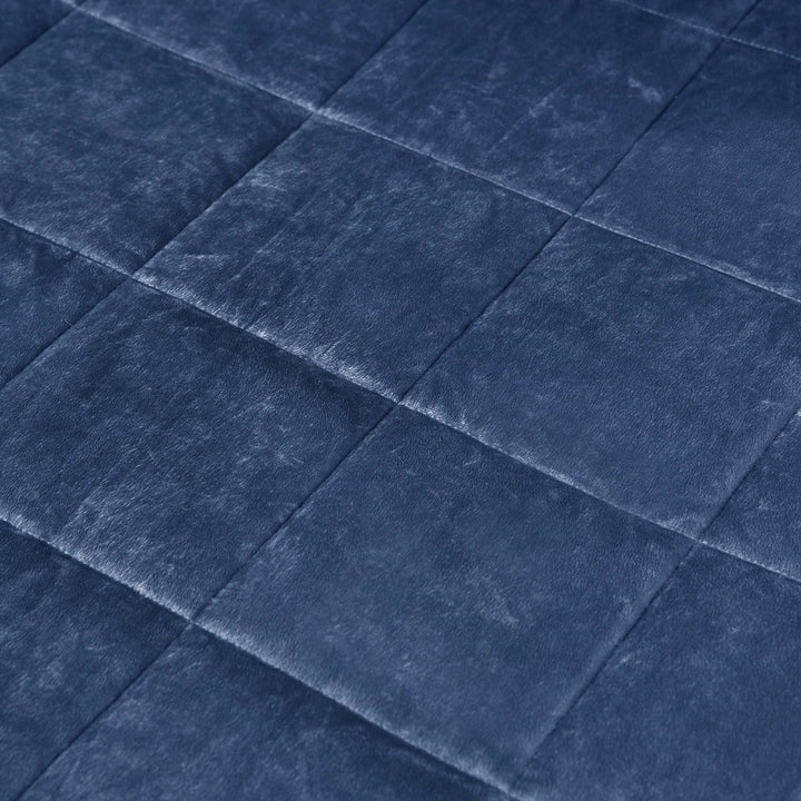 Schlafzimmer mit gefalteter, beschwerter Decke auf dem Bett. Eine ruhige Schlafhilfe für Entspannung und Antistress.