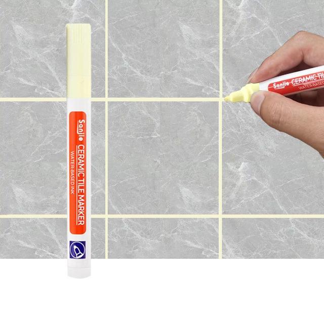Eine Person reinigt Fliesenfugen mit dem Fugenstift, um Verfärbungen zu entfernen.