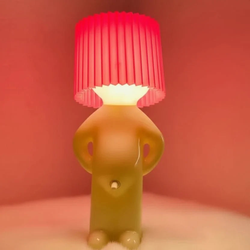 Die verspielte LED Kinderzimmerlampe auf einem Regal neben Büchern, warm und einladend leuchtend.