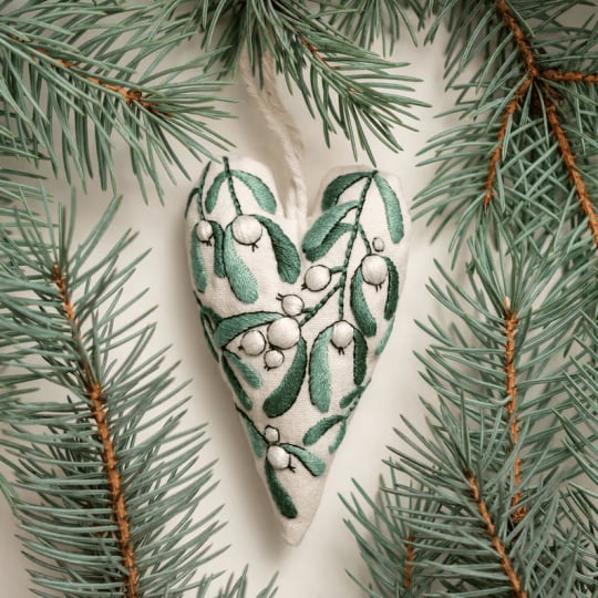 Nahaufnahme des DIY Sticksets: Garn, Nadeln, Stoff & Anleitungen für Herz-Ornamente.
