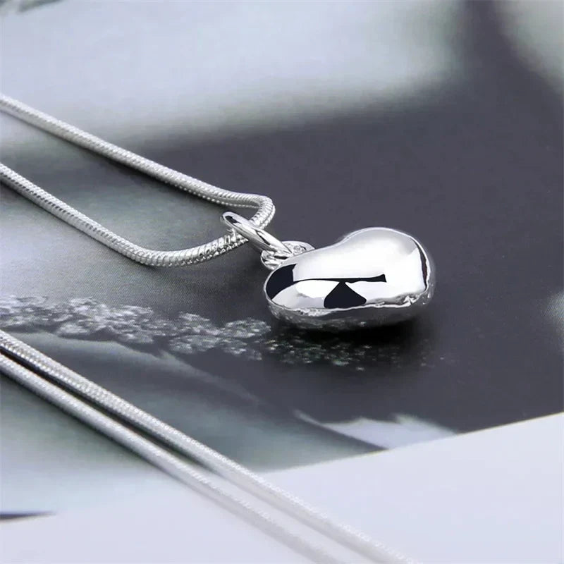 Detailaufnahme einer eleganten 925 Sterling Silber Schlangenkette mit poliertem Herzanhänger, Damenschmuck.