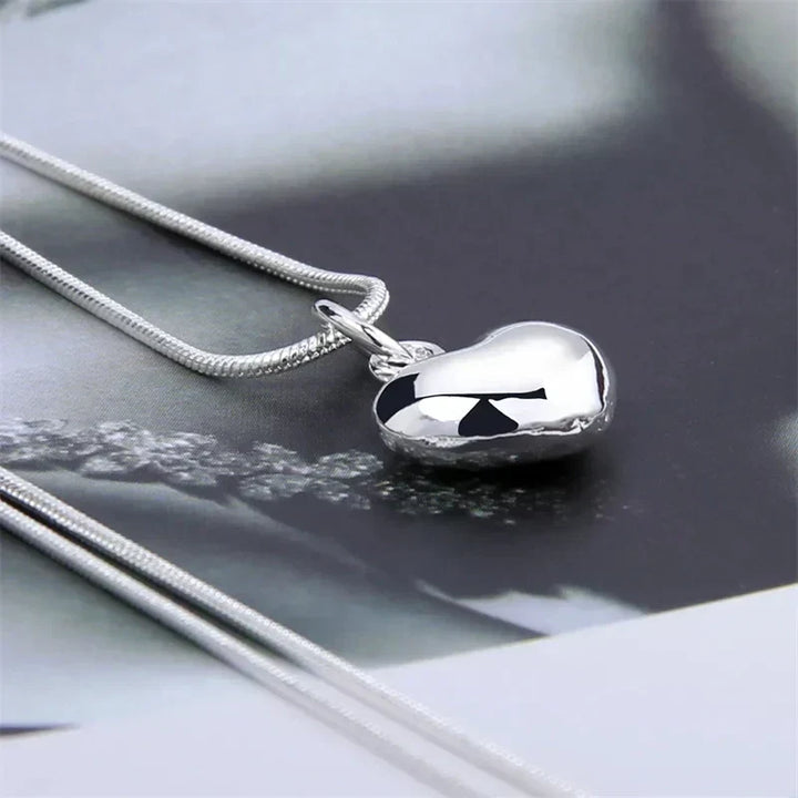 Detailaufnahme einer eleganten 925 Sterling Silber Schlangenkette mit poliertem Herzanhänger, Damenschmuck.