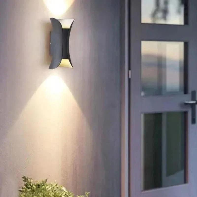Geschwungene LED-Außenleuchte aus Metall, IP65, perfekt als Terrassenbeleuchtung mit modernem Flair.