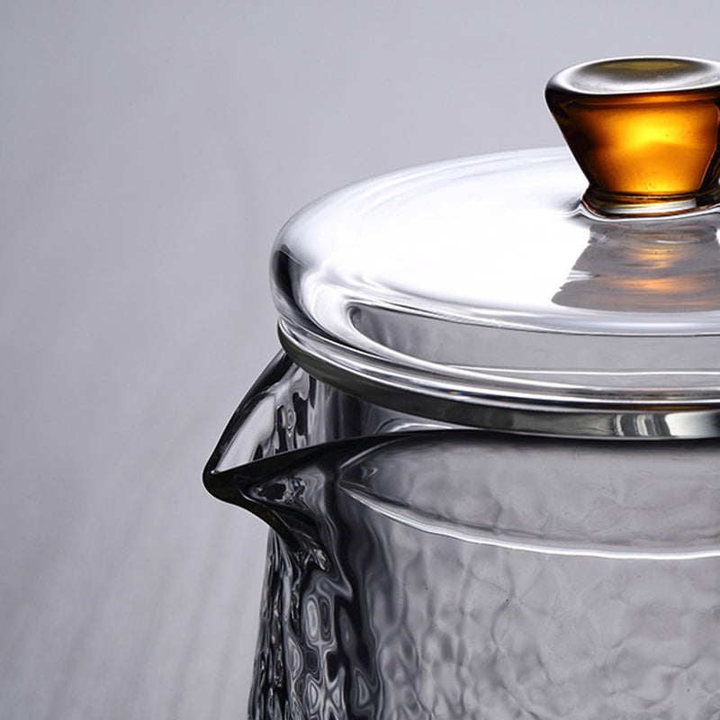 Teekanne aus Glas mit Sieb, beim Ausgießen von aromatischem, frisch gebrühtem Tee.