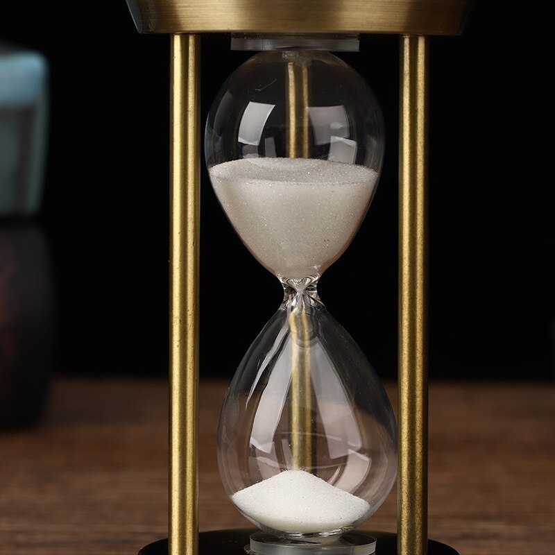 Nahaufnahme einer Retro-Sanduhr mit feinen Details, die den Vintage-Metallrahmen und den fließenden Sand zeigt.