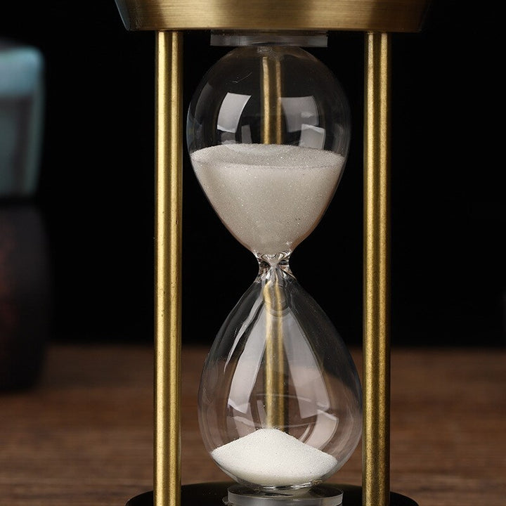 Nahaufnahme einer Retro-Sanduhr mit feinen Details, die den Vintage-Metallrahmen und den fließenden Sand zeigt.