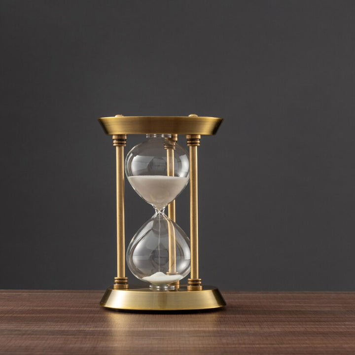 Bronze-Sanduhr im Retro-Design auf einem Holzschreibtisch. Ein elegantes Desktop-Ornament und praktischer Zeitmesser.