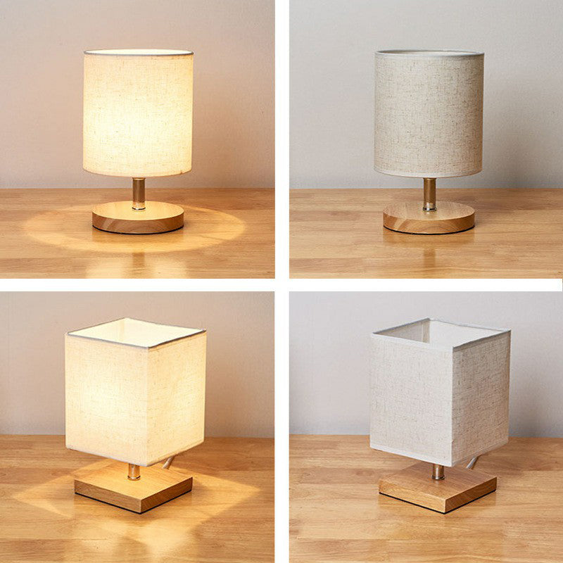 Elegante Tischlampe mit Holzsockel und Leinen-Schirm, ideal für stimmungsvolle Beleuchtung in Wohn- oder Schlafzimmer.