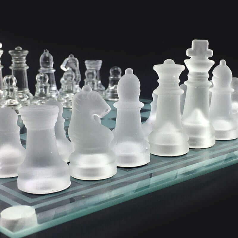 Elegantes Glas-Schachspiel mit mattierten Kristallfiguren auf poliertem Schachbrett.