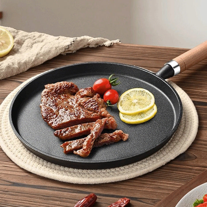 Gusseisenpfanne auf dem Herd: Schwarze, antihaftbeschichtete Bratpfanne aus Gusseisen, bereit zum Kochen.