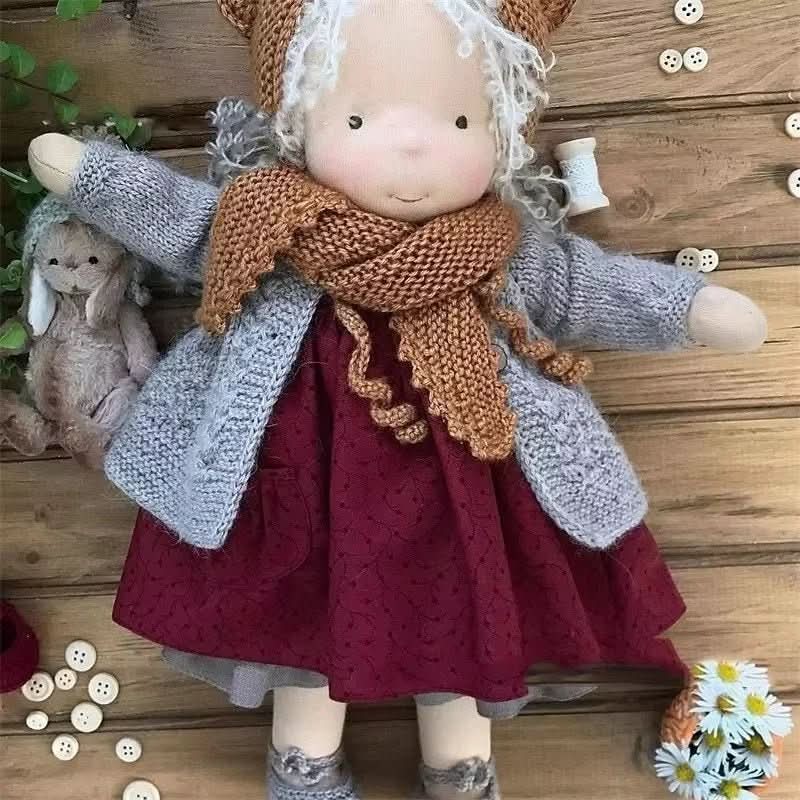 Detailaufnahme der Waldorf-Puppe: handgesticktes Gesicht, rosige Wangen, rote Baumwollhaare, ungiftiges Spielzeug.