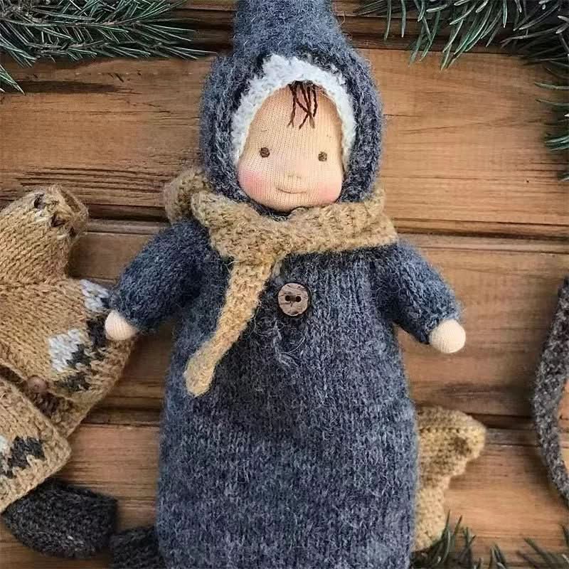 Waldorf-Puppe trägt eine warme, handgestrickte Mütze und Schal, passendes Puppenzubehör für Wintertage.