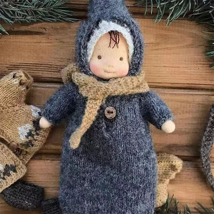 Waldorf-Puppe trägt eine warme, handgestrickte Mütze und Schal, passendes Puppenzubehör für Wintertage.