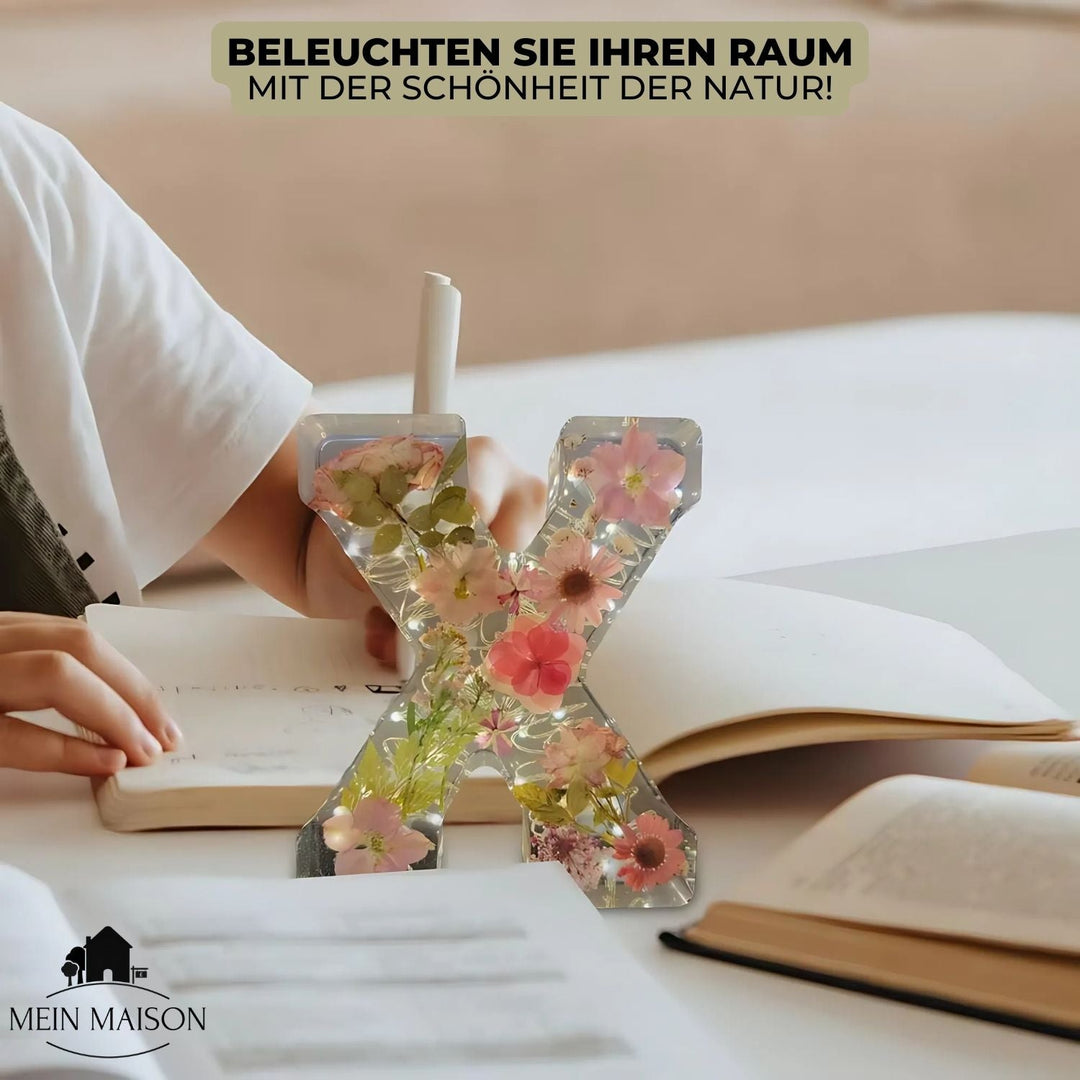 Detailansicht eines Harzbuchstabens mit filigranen, getrockneten Blumen und glänzender Harzoberfläche.