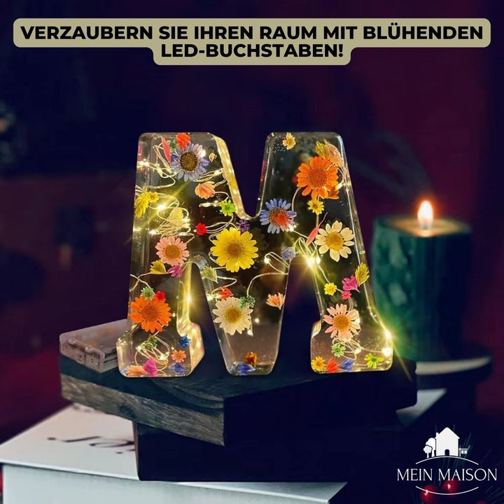 Eleganter LED Harzbuchstabe als blumige Dekoration auf einem Regal im hellen Wohnzimmer.