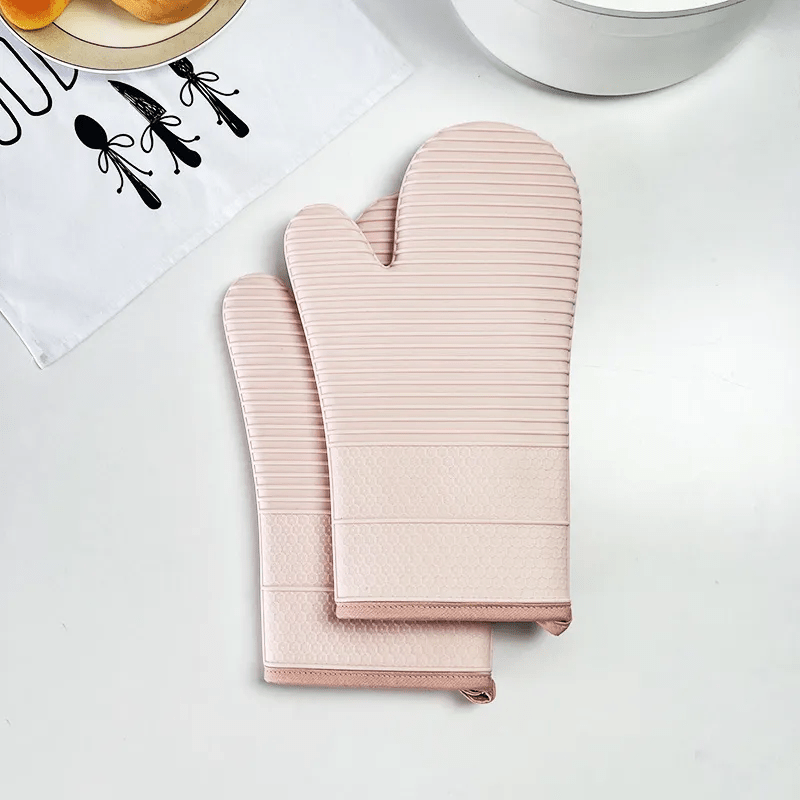 Zwei HEATSAFE Ofenhandschuhe hängen bereit in einer modernen Küche, symbolisieren Sicherheit und Kochfreude.
