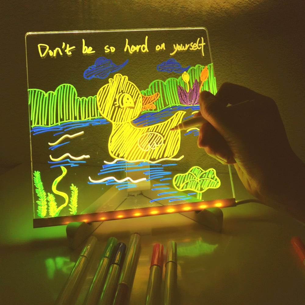 Glückliches Kind malt mit bunten Lichtern auf der LED-Kreativtafel; pädagogisches Zeichentafel Spielzeug.