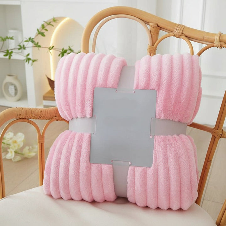 Gestreifte Flanell-Fleece-Kuscheldecke drapiert auf einem Bett, für einladende Wärme und ein stilvolles Ambiente.