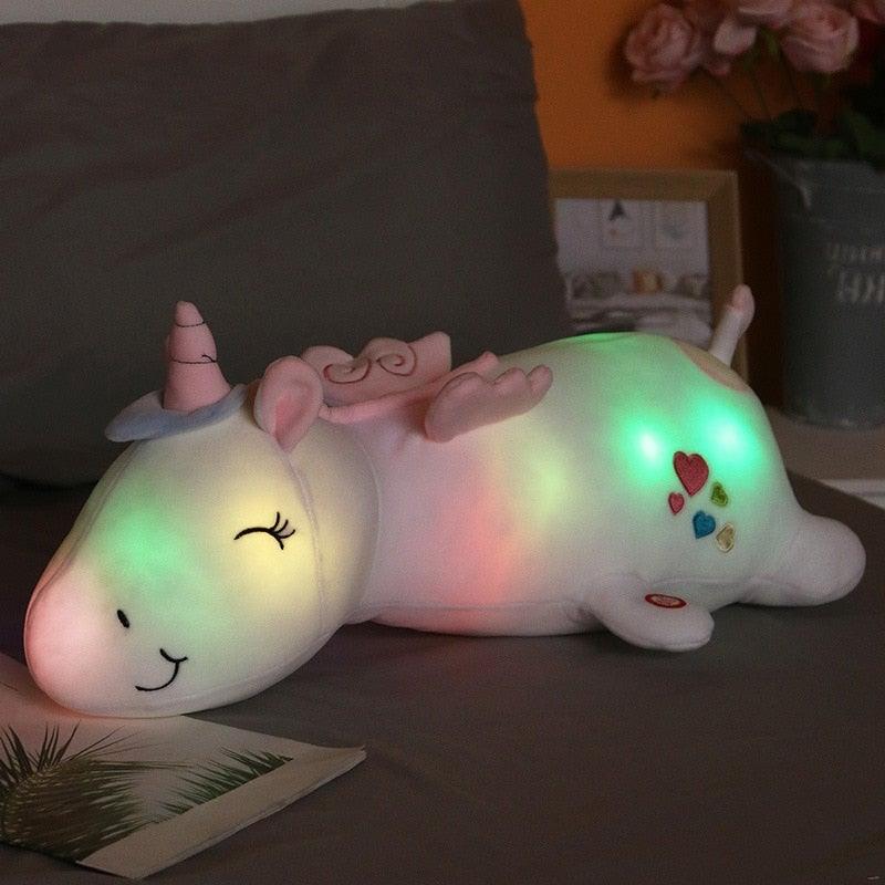 Leuchtendes Einhorn-Plüschtier 60cm auf Bett. Farbwechsel-LED Kuscheltier und Nachtlicht für süße Kinderträume.