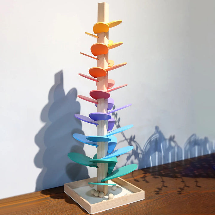 Kind spielt mit Luca Regenbogen-Murmelturm. Murmel rollt durch den bunten Klangbaum, erzeugt schöne Töne.