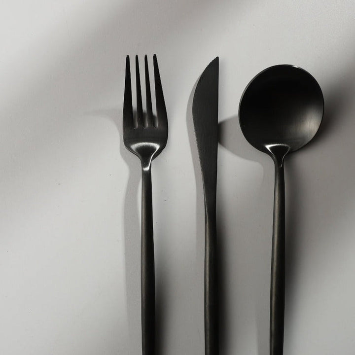 Minimalistisches Besteckset in Matt-Schwarz, präsentiert auf einem modernen, stilvollen Besteckständer.