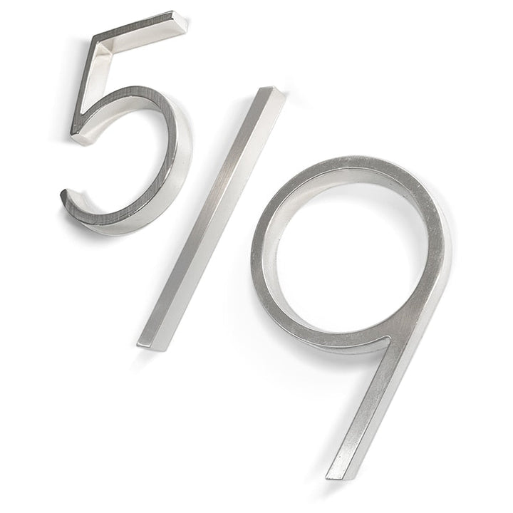 Nahaufnahme einer glänzenden silbernen Hausnummer "7", akzentuiert modernes Außendesign.