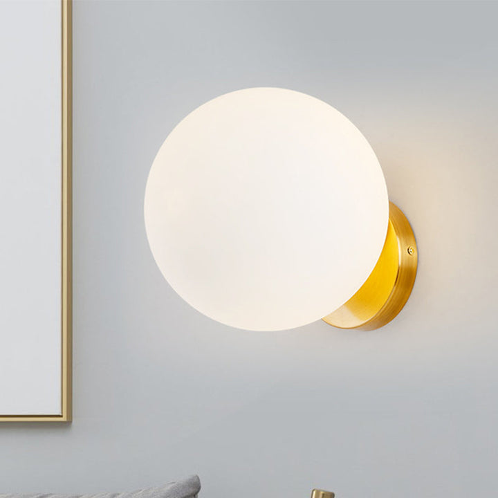 Stilvolle Wandlampe mit mattem Glaskugel und goldenem Sockel. Eine minimalistische Innenbeleuchtungslösung.