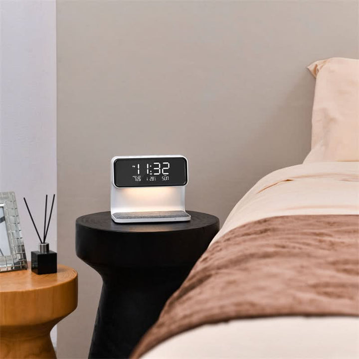 Smartphone wird kabellos auf multifunktionalem LCD-Wecker mit dimmbarer LED-Nachttischlampe geladen.