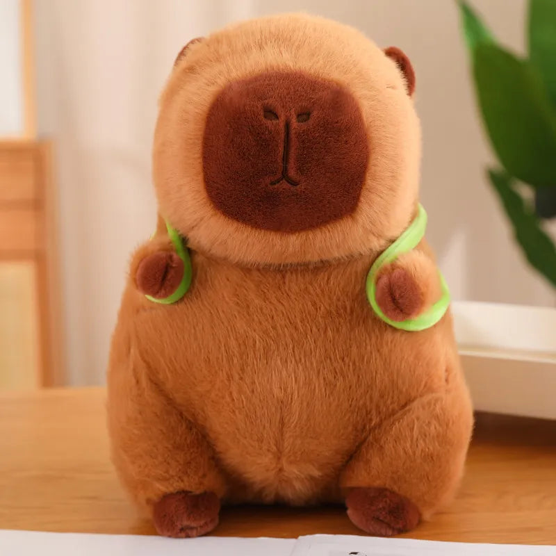 Detailansicht: Süßes Capybara Plüschtier trägt einen kleinen grünen Schildkröten-Rucksack auf dem Rücken.