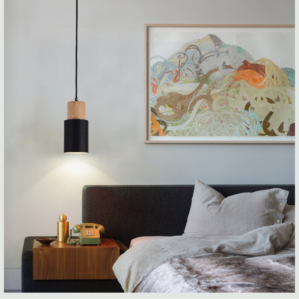 Nahaufnahme einer nordischen Pendelleuchte: detaillierter Holzsockel und modernes Kabeldesign.