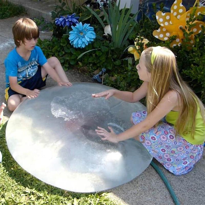 Kind lacht und spielt mit dem riesigen, dehnbaren Bubble Ball im Grünen. Outdoor-Spielspaß garantiert.