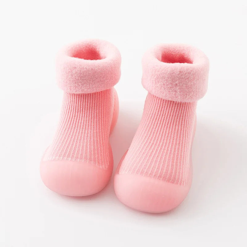 Kleinkind trägt warme, rutschfeste Sockenschuhe beim Spielen, ideal für Mobilität und Schutz der Füße.