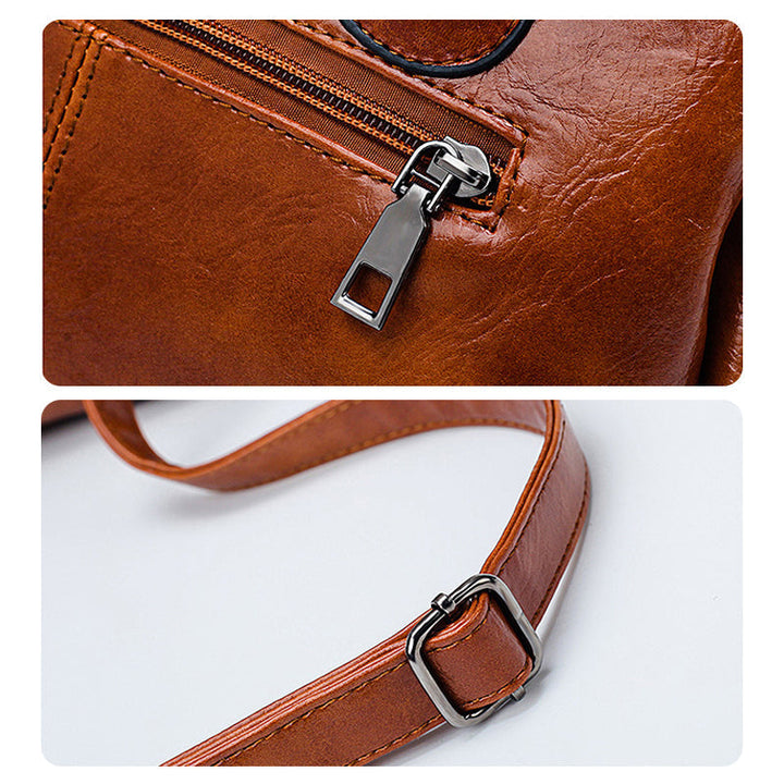 Elegante schwarze Boston Damen Umhängetasche aus Ölwachsleder auf Tisch. Retro, weiche Leder-Handtasche.