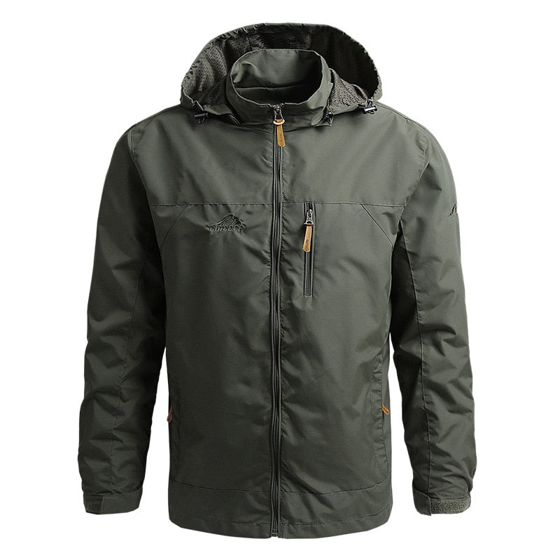 Mann in taktischer, wasserdichter Herren Outdoorjacke mit Kapuze beim Wandern in den Bergen.