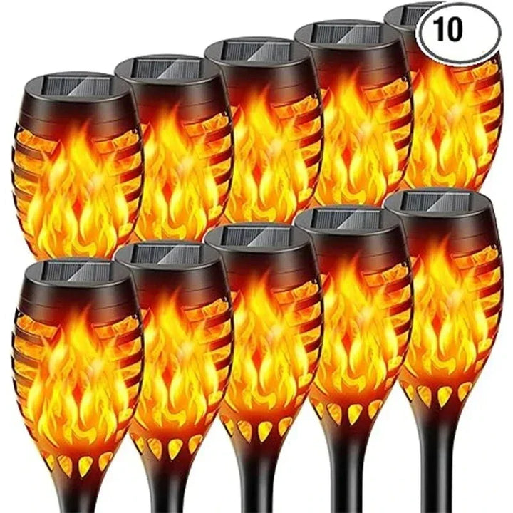 Mehrere Solar-Wegeleuchten mit Flammeneffekt säumen einen Gartenweg, schaffen warme, einladende Atmosphäre.