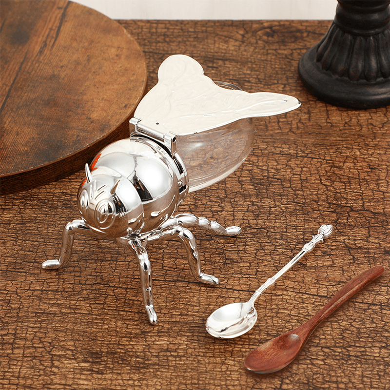 Praktischer Honigspender aus Glas mit Löffel, erleichtert das Dosieren von süßen Speisen am Tisch.