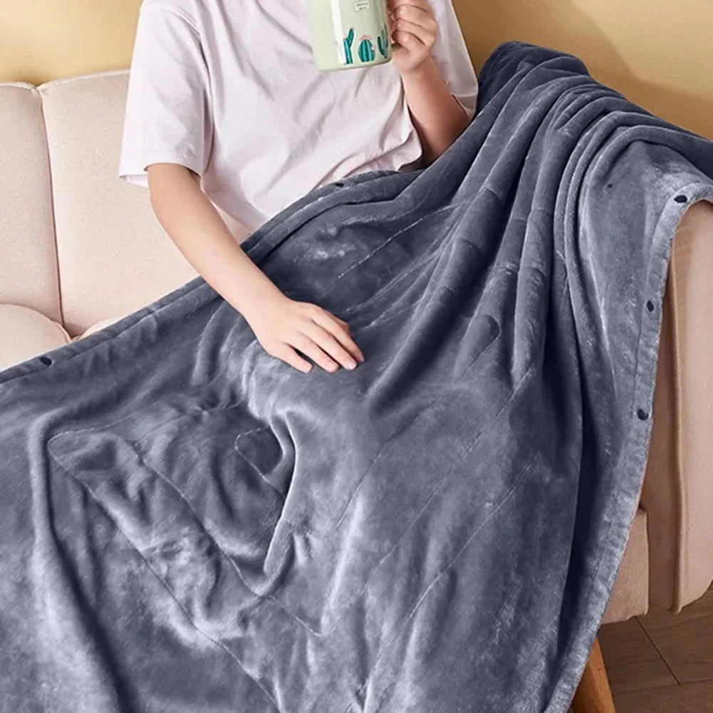 Person auf Sofa, eingewickelt in warme USB-Heizdecke, genießt entspannt die angenehme Wärme.