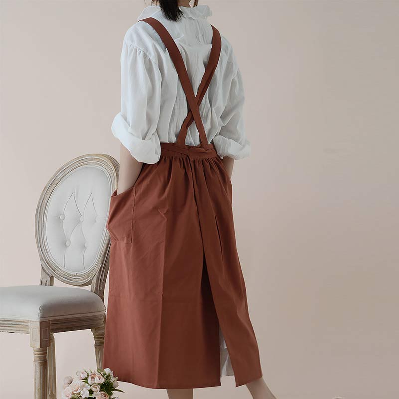 Elegante Küchenschürze in neutralem Farbton, mit Kreuzgurt und cleveren Taschenlösungen.