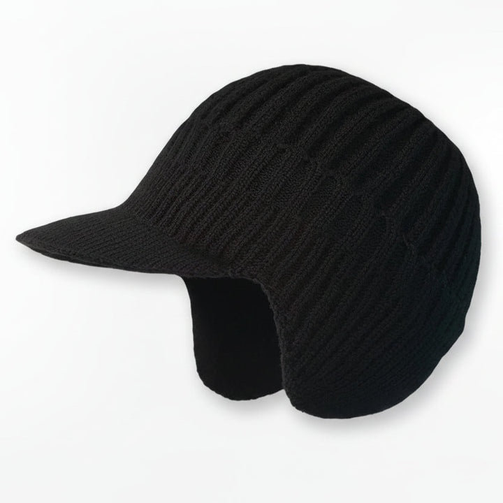 Gemütliche Nordic-Wintermütze auf einem schneebedeckten Baumstamm, bereit für den Winter.