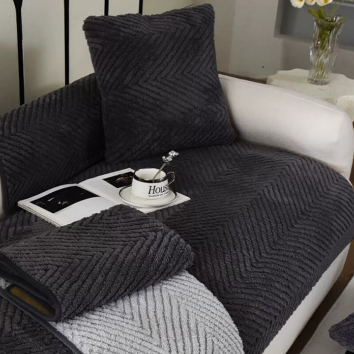 Gemütlicher Plüsch-Sofabezug in Beige mit Fischgrätenmuster. Rutschfester Sofaschutz für warmes Wohnzimmer.